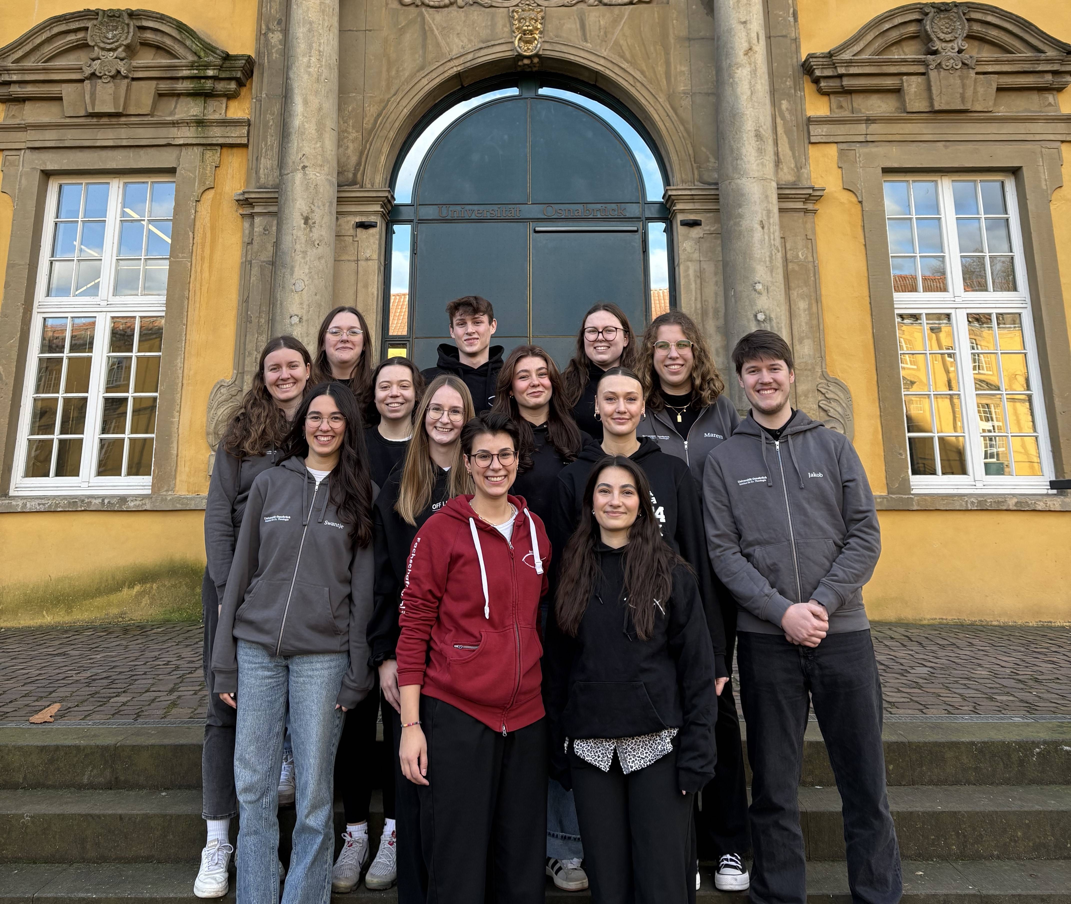 Die Studierenden der Fachschaft stehen auf der Schlosstreppe und lächeln in die Kamera